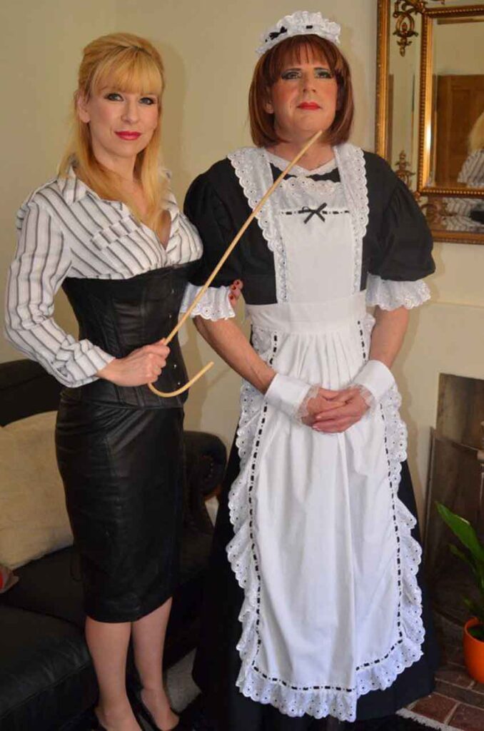 a sissy maid posing with mistress and cane