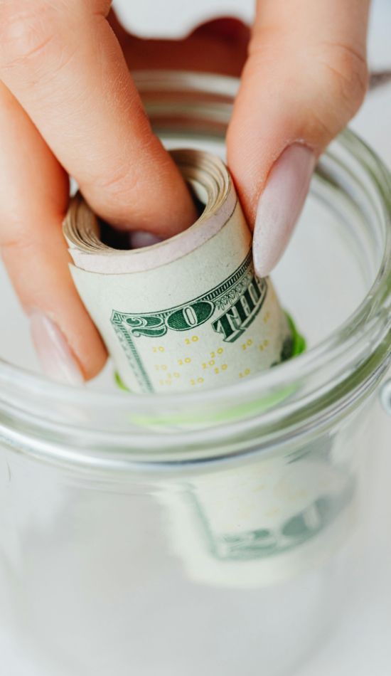 rolled up dollars being placed in a jar