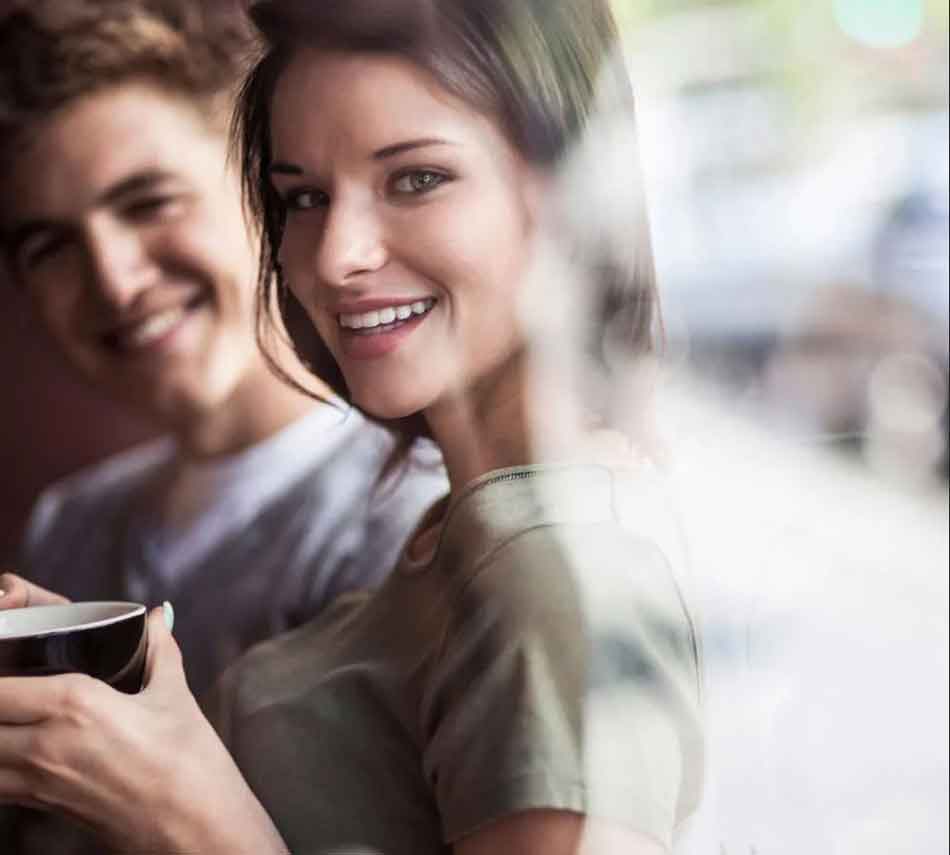 a misrtess holding a coffee with man behind